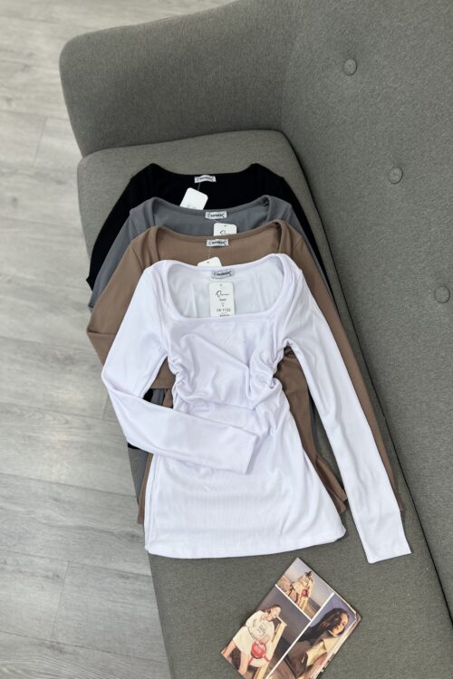 Ky imazh tregon katër bluza me mëngë të gjata dhe jakë katrore, të vendosura njëra mbi tjetrën në një divan gri.